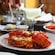 A table set with a plate of lobster, side dishes and a cocktail